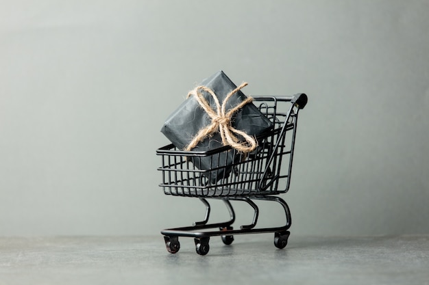 Black shopping cart and gift box on gray background