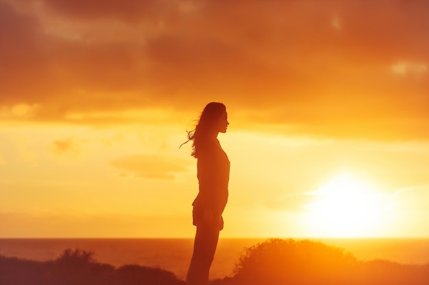 Black silhouette of pretty girl on sea beach at sunset