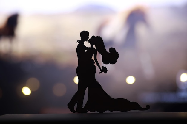 Black silhouettes of pair dancers performing Man and woman are dancing on gray background with white backlight Choreography New Year's ball