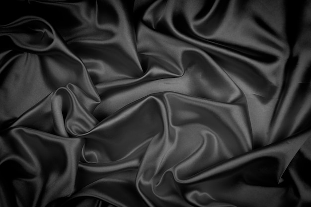 Black silk texture luxurious satin for abstract background. Dark tone of fabric