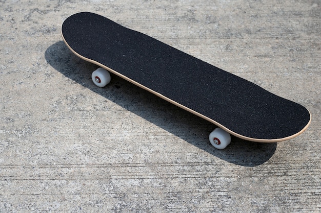 Black skateboard on cement ground.