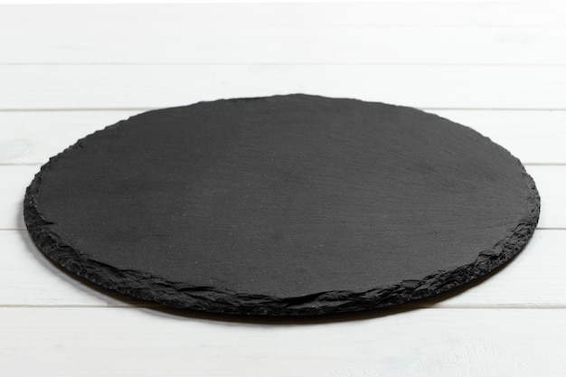 Pietra rotonda dell'ardesia nera su fondo di legno