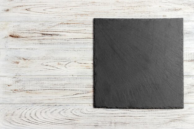 Photo black slate stone on wooden background copy space