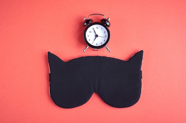 Black sleep mask with clock on pink composition, cat mask with ears