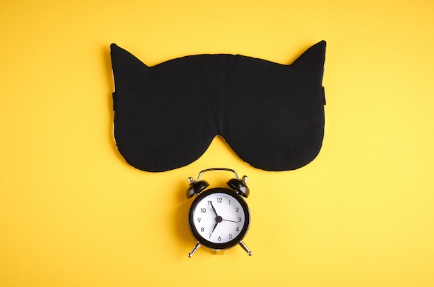 Black sleep mask with clock on yellow composition, cat mask with ears