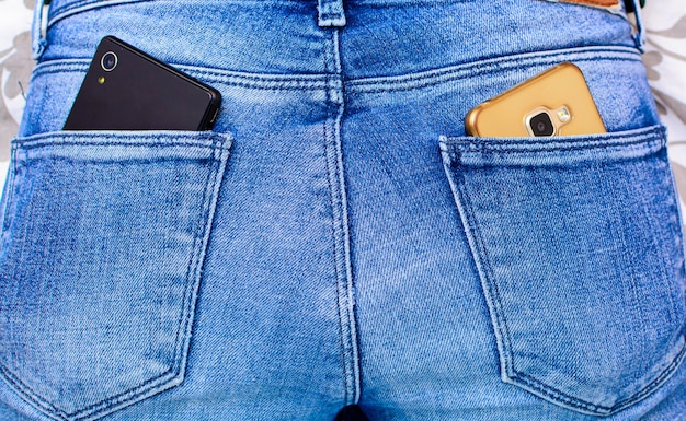 Foto smartphone nero nella tasca posteriore dei jeans da ragazza