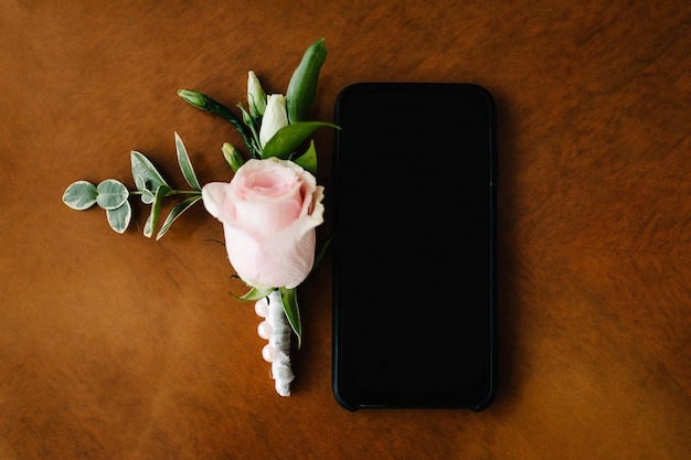 Smartphone nero con uno schermo vuoto chiaro su sfondo marrone piatto vista dall'alto telefono con uno schermo vuoto con spazio rosa rosa per il testo dell'applicazione concetto di saluto regalo di vacanza