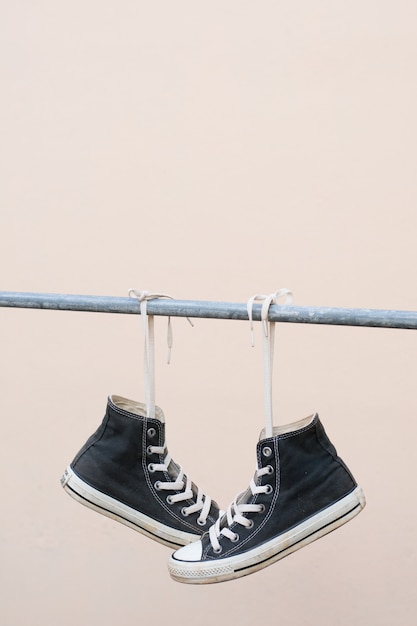 Black sneakers hanging on metal bar