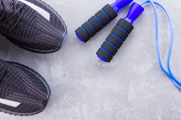 Black sneakers and jump rope on gray background