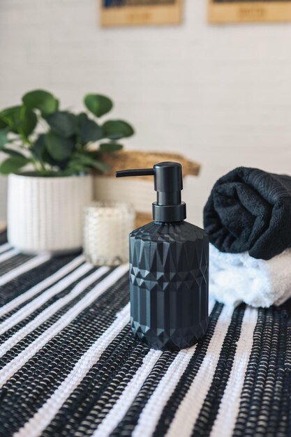 Black soap dispenser in a stylish Scandinavian bathroom against the background of towels