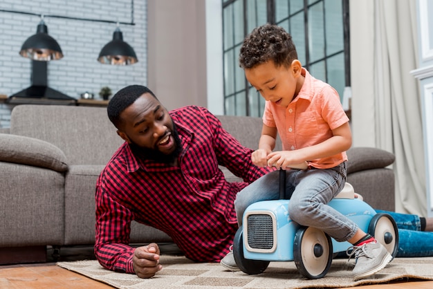 black son driving toy car with father 