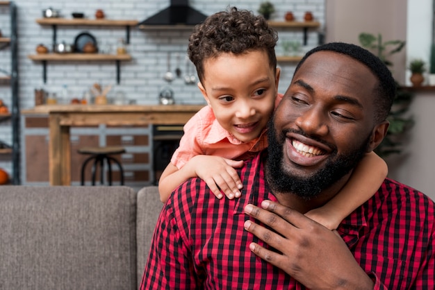 Black son hugging father from behind 