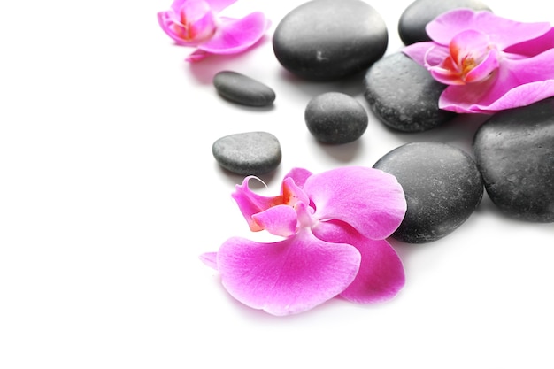 Black spa stones and orchids isolated on white