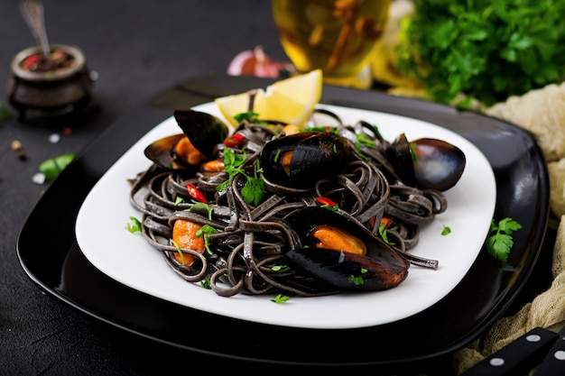 Black spaghetti. Black seafood pasta with mussels over black background