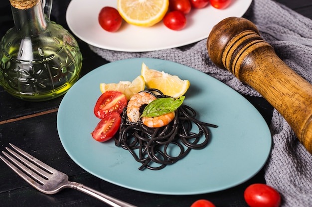 Черные спагетти с креветками на белой тарелке