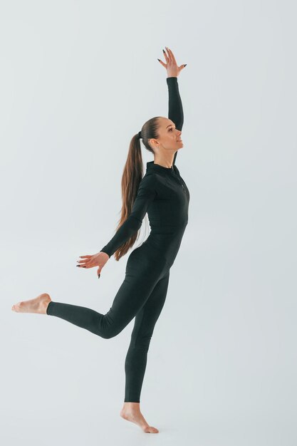 In black sportive clothes young woman doing gymnastics indoors