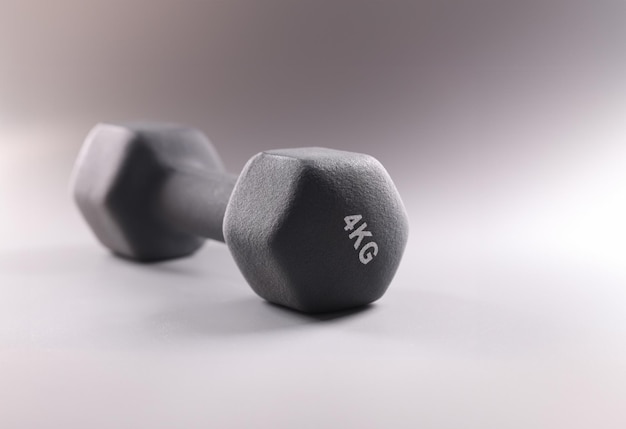 Black sports dumbbell for bodybuilding on gray background closeup