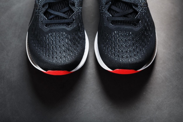 Sneakers sportive nere con suole rosse su sfondo nero. Foto Premium