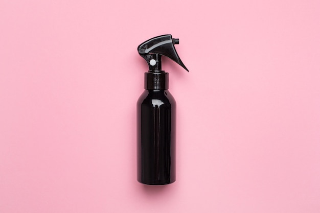 Black spray bottle on pastel pink