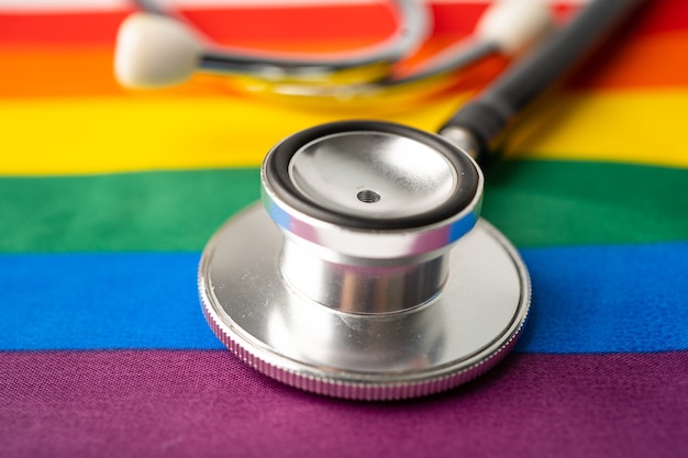 Черный стетоскоп на радужном флаге, символе месяца гордости ЛГБТ, ежегодно отмечаемом в июне, социальном, символе геев, лесбиянок, бисексуалов, трансгендеров, прав человека и мира.