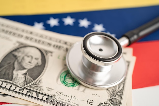 Photo black stethoscope with us dollar banknotes on venezuela flag background business and finance concept