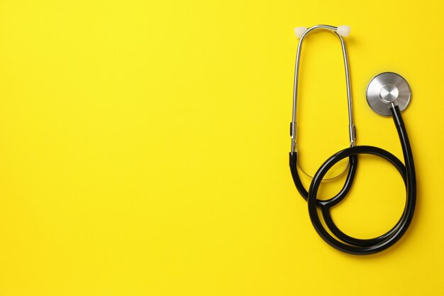 Black stethoscope on yellow surface