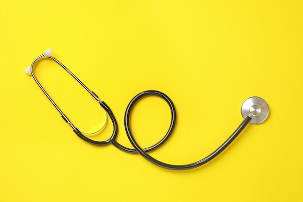 Black stethoscope on yellow, top view