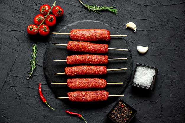 A black stone background with meat skewers and spices.