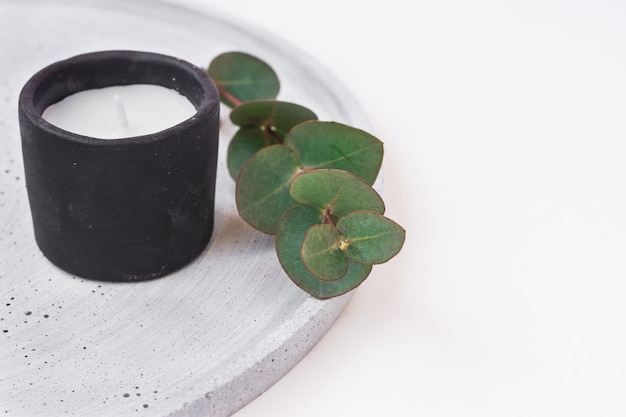 Black stone candle dry branch of green eucalyptus on white background