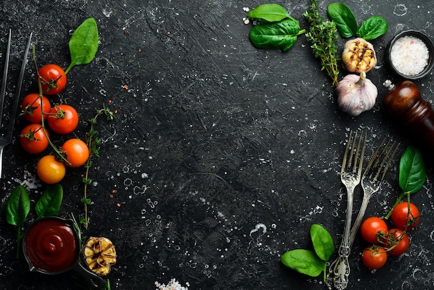 Black stone cooking background fresh vegetables and spices on a\
stone table top view