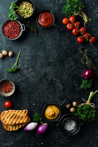 Black stone cooking background Spices and vegetables Top view Free space for your text