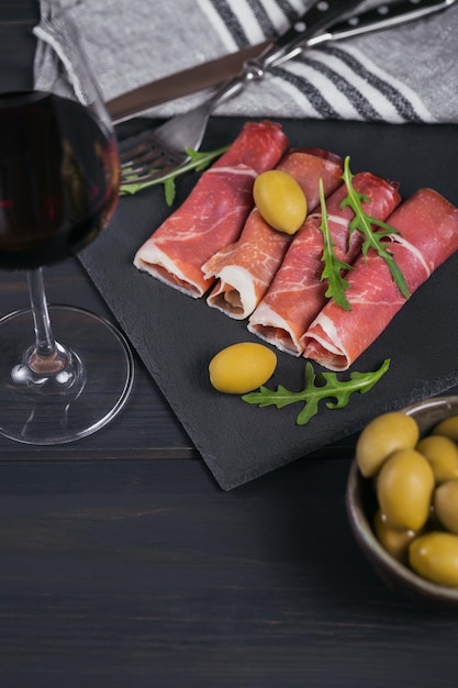 Black stone platter with slices of cured ham or spanish jamon serrano or italian prosciutto crudo