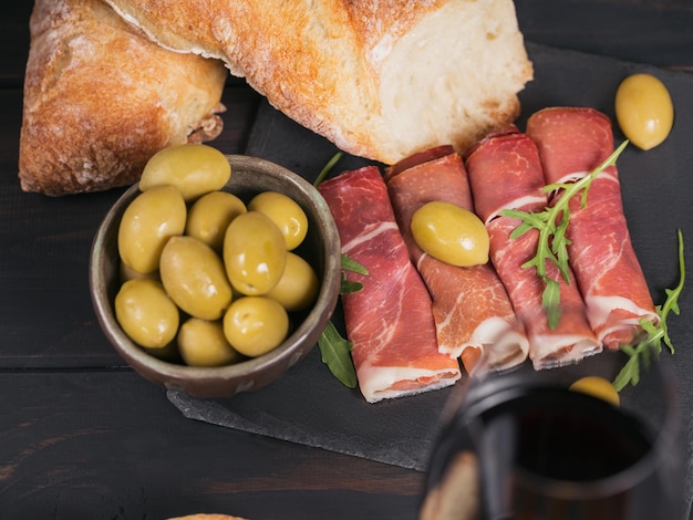 Black stone platter with slices of cured ham or Spanish jamon serrano or Italian prosciutto crudo