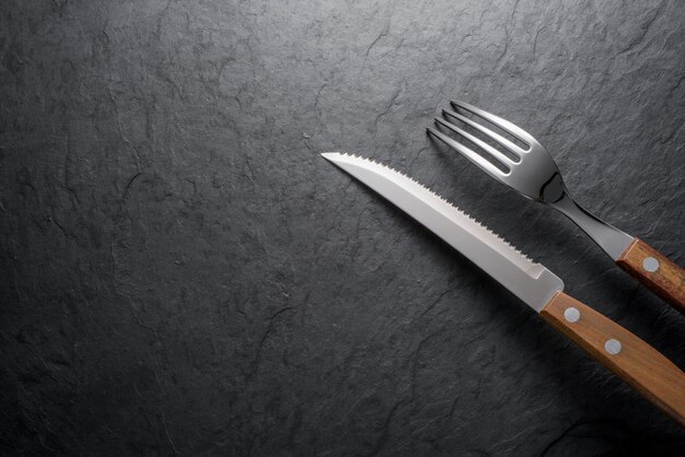 Black stone slate board with fork and knife top view