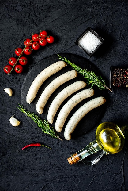 A black stone surface with various ingredients including sausages, olive oil, and olive oil.