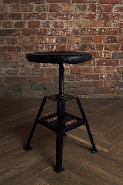 Photo black stool on an old brick wall background