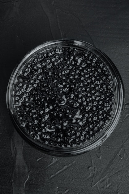 Black sturgeon caviar jar, on black table, top view flat lay