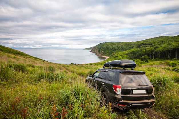 Черный Subaru Forester с боксом на крыше по дороге к морю