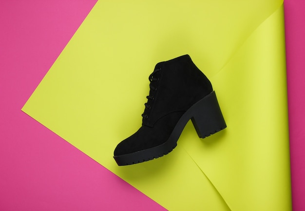 Black suede boot on neon folded paper