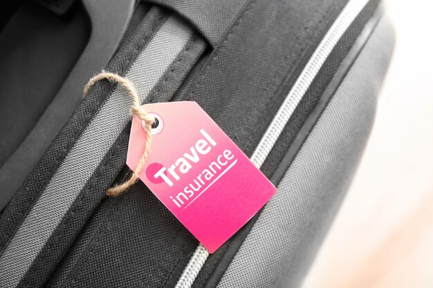 Black suitcase with label closeup TRAVEL INSURANCE concept