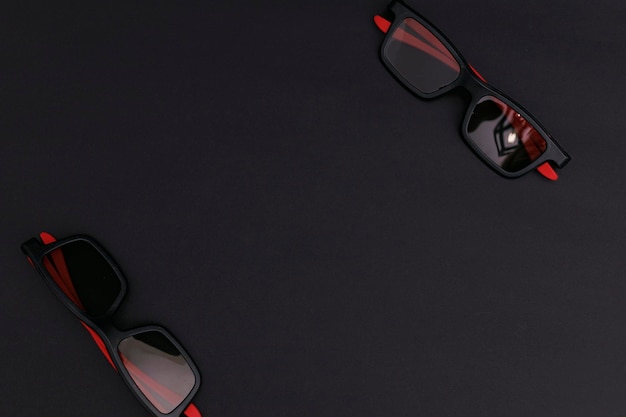 Black sunglasses lying on a black background background