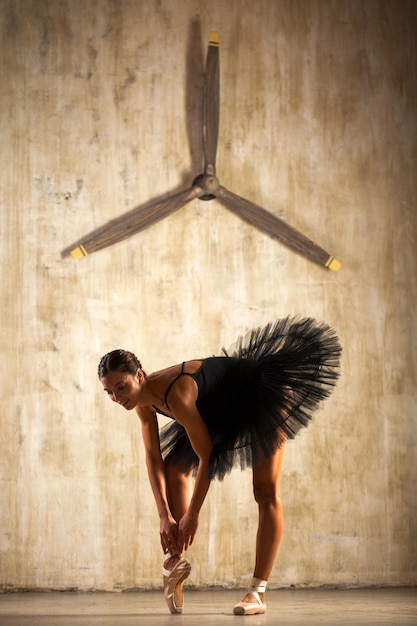 Фото Портрет молодой красивой балерины в черном балетном туту, позирующей в студии