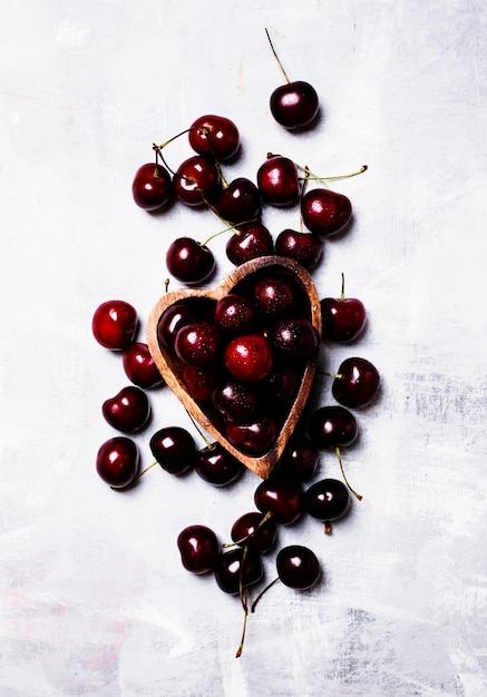 Black sweet cherries in bowl in shape of heart top view