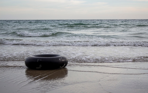 Photo black swim ring on the beach in the evening rubber ring floating in the sea.