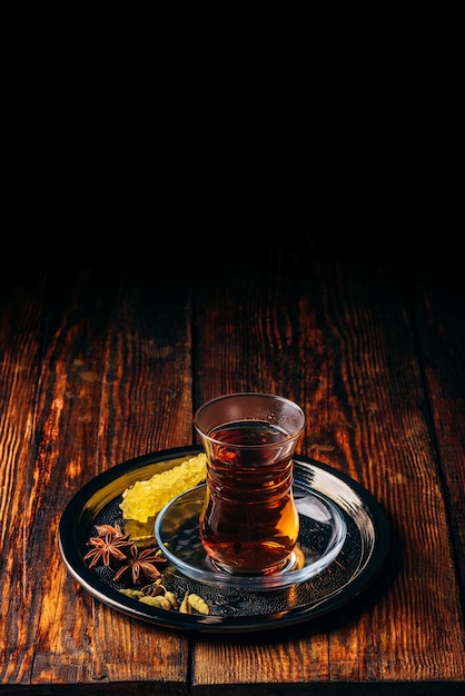 черный чай в бокале армуду с звездчатым анисом и зеленым кардамоном с хрустальным сахаром на металлическом подносе