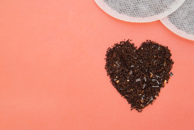 Black tea heart shape isolated on pink . Tea isolated.