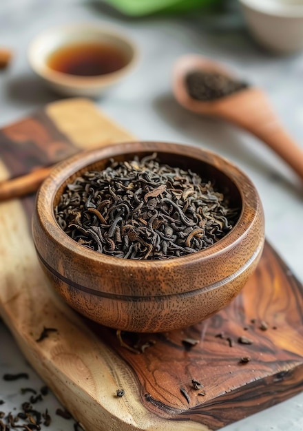 Photo black tea leaves in a wooden bowl on a wooden table