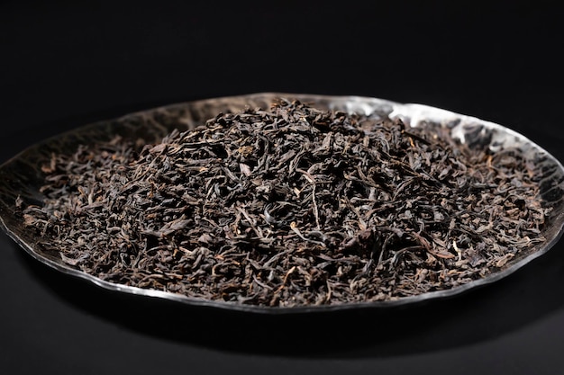 Black tea loose dried tea leaves in a black stone plate marco