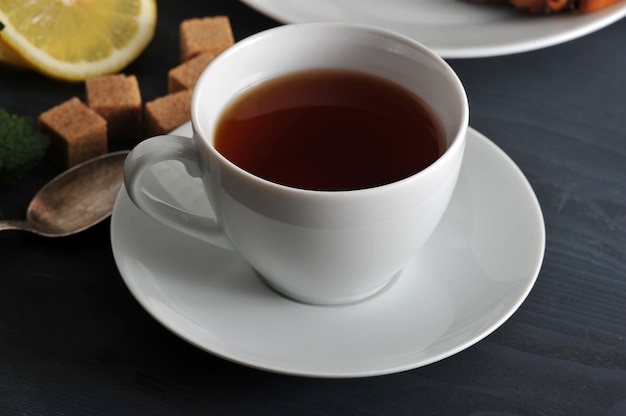 Black tea in a mug on a saucer, lemon and mint 