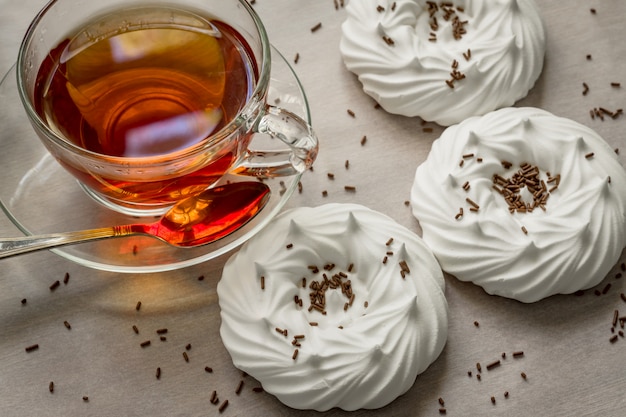 Black tea in transparent cup an air homemade meringues close up